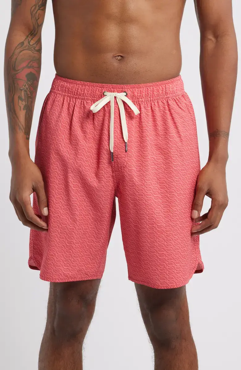 A person wearing pink patterned swim trunks with a white drawstring, standing against a plain background—perfect for Dad’s next summer vacation.