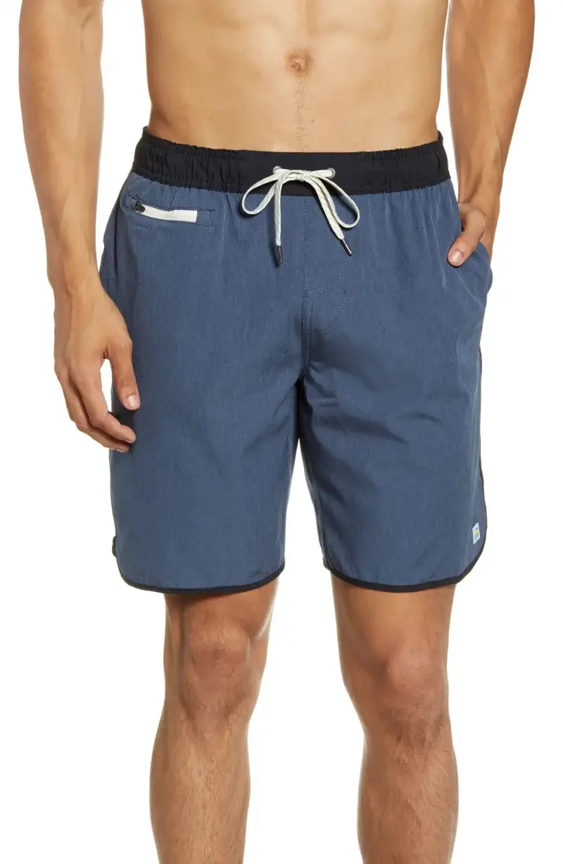 A man wearing blue drawstring swim trunks with black waistband and trim, standing with hands in pockets—perfect for summer vacation or as a stylish choice for Father’s Day gifts.