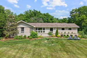 A single-story house at 612 Lamar Dr, Nashville TN, with light siding and a well-maintained front yard featuring shrubs, small trees, and a set of four blue outdoor chairs on the right side.
