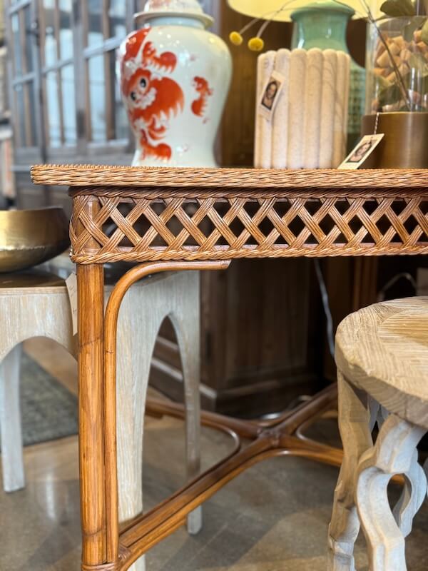 A wicker table with a lattice design stands among other wooden furniture and a decorative ceramic vase, adding charm to the home decor in this Nashville furniture-filled room.