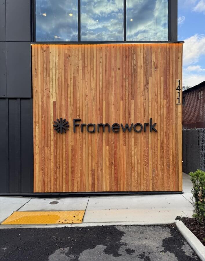 A building exterior features a wood-paneled wall with the word "Framework," a star-like logo.