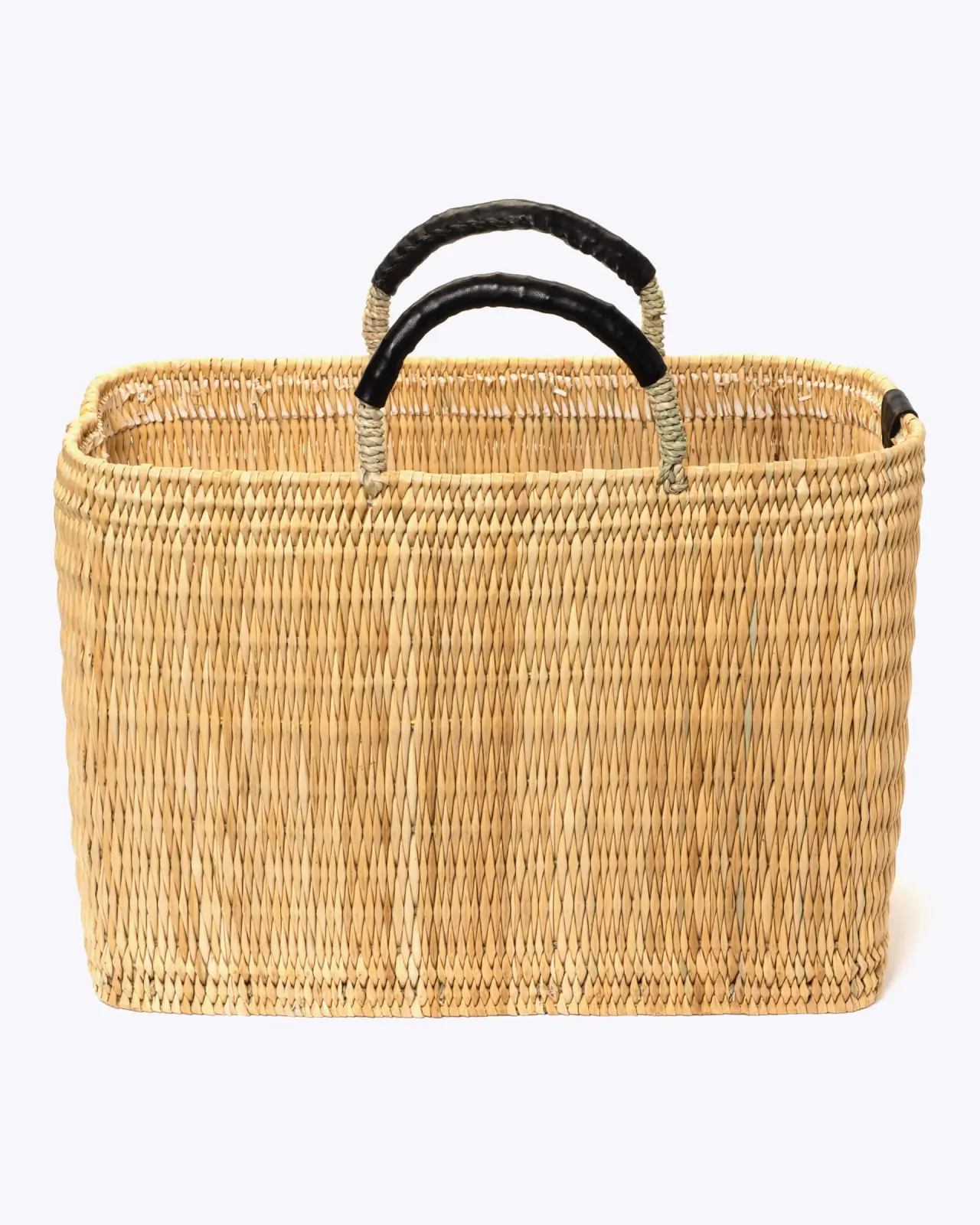 Rectangular woven basket with two black-wrapped handles, made from natural straw material, displayed on a plain white background—an elegant pick for the June 2025 SB Hot List.