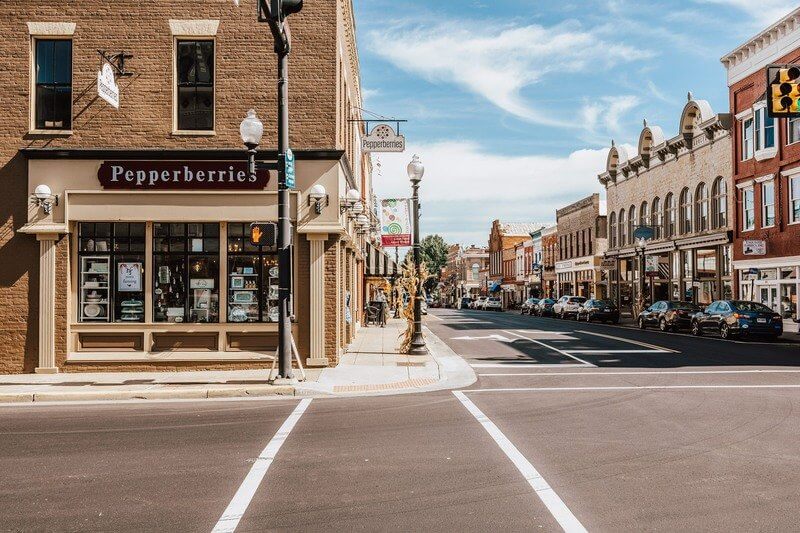 A view of a quiet downtown street intersection lined with historic brick buildings, shops, and parked cars under a partly cloudy sky—one of Virginia’s must-visit places for travel enthusiasts.
