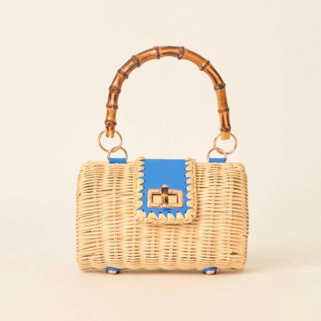 22 Birmingham FINDS for June: Breezy Dresses, Entertaining & Gifts for Dad - 7 Perfect for summer shopping, this woven straw handbag features a bamboo handle, blue leather trim, and a gold clasp, displayed against a neutral background.