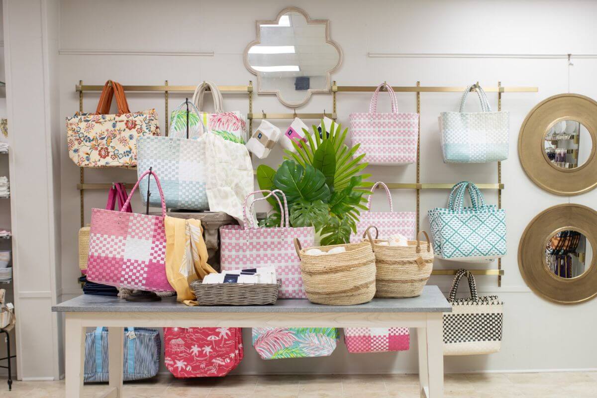 A display of colorful woven bags and baskets arranged on a table and hanging on a wall in one of the new shops in Birmingham, with mirrors and a decorative wall mirror in the background.