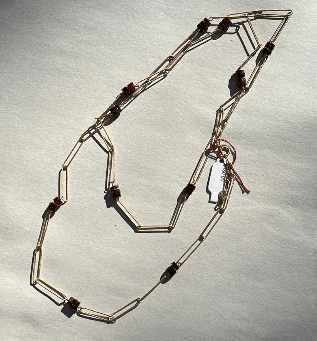 Gold-tone Luxe necklace with elongated chain links and clusters of small reddish beads.