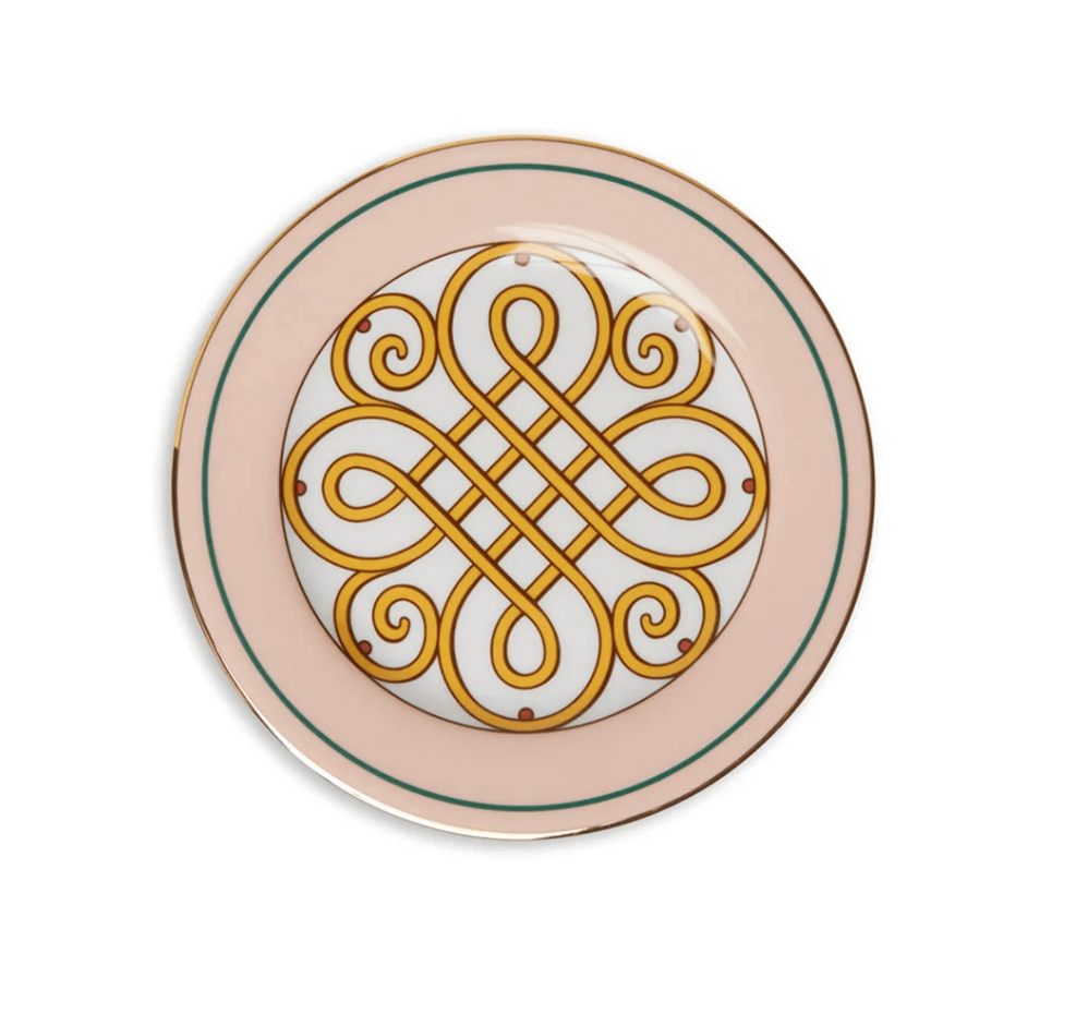 A decorative plate with a pink border, gold rim, and a central intricate gold and yellow geometric pattern on a white background—a charming June find from Birmingham.