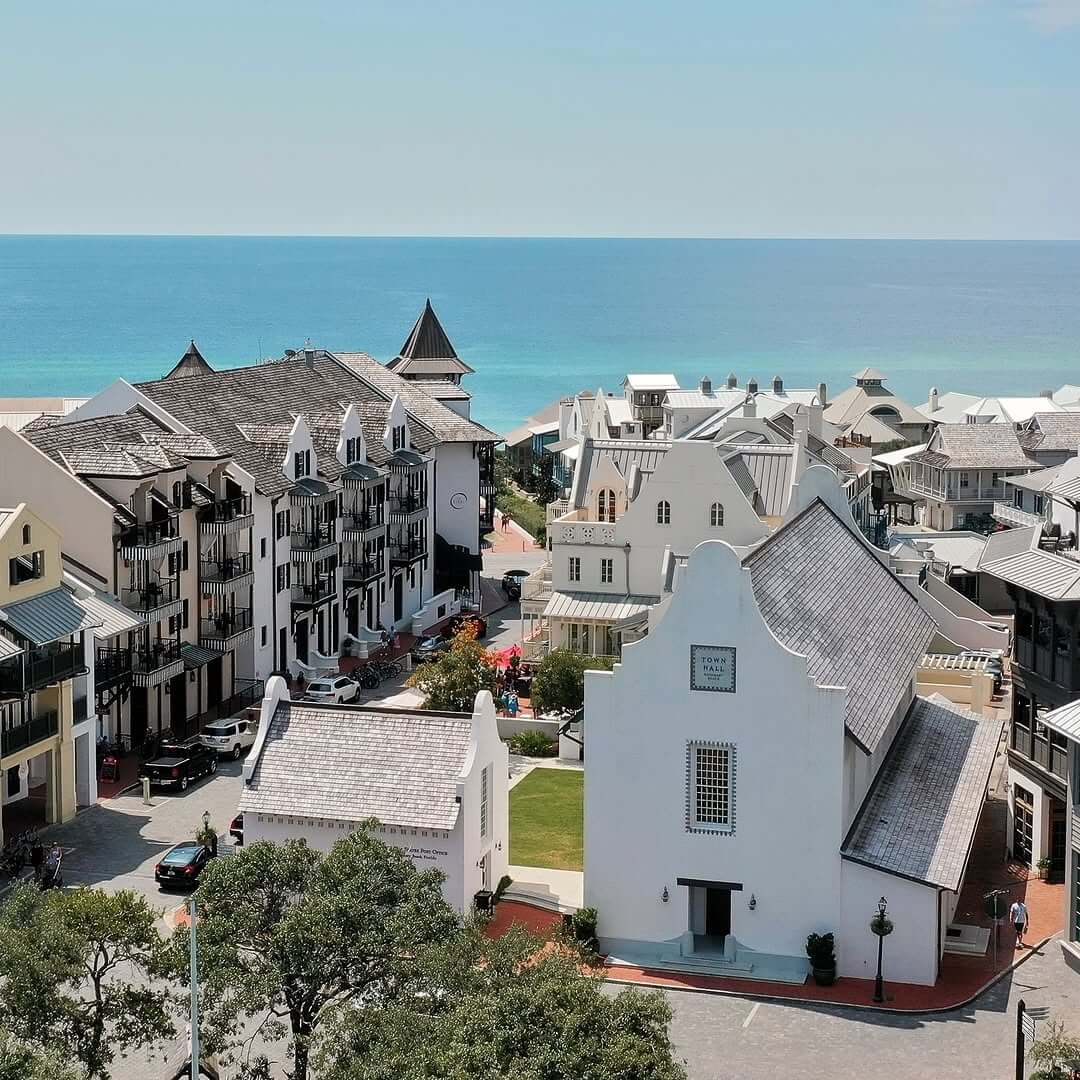 Rosemary Beach in 30A with white buildings and a church in the foreground, perfect for weekend getaways, overlooks the ocean under a clear sky.