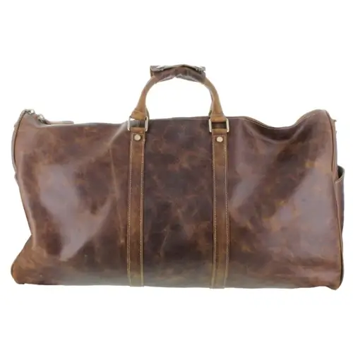 A large brown leather duffel bag with two handles and a side pocket, perfect for summer 2025 getaways or a stylish trip to Memphis, shown against a white background.