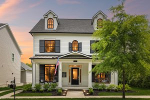 Just listed! This storybook cottage is a stunning two-story white house with black shutters, front porch, and an American flag. Beautifully landscaped yard, captured perfectly at sunset—your Franklin Cottage dream awaits.