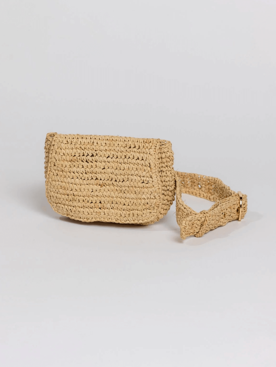A woven straw belt bag with a flap closure and adjustable strap from FINDS, June collection, displayed against a plain light gray background.