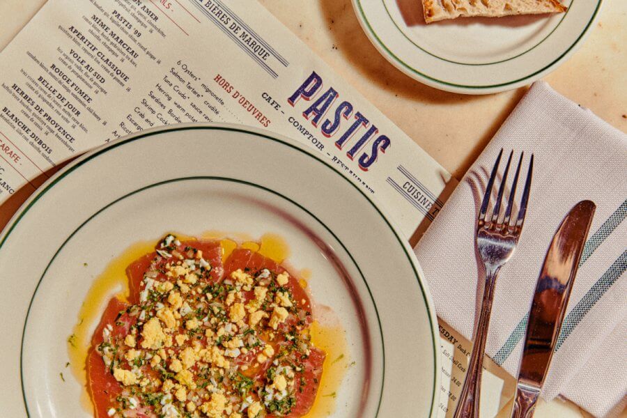 Nashville’s 10 Most Popular Articles of 2025 - 11 A plate of tomato salad with chopped egg and herbs sits on a table next to a menu, bread, and silverware.