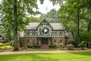 Charming two-story Tudor-style house at 6470 Corsica Dr, Memphis, with brick and half-timbered facade, surrounded by trees and a landscaped yard on a sunny day.