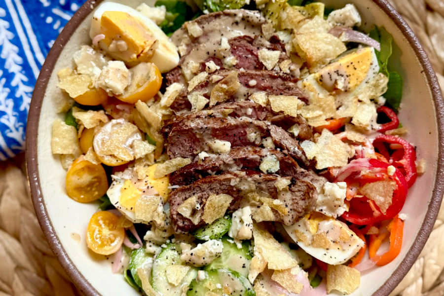 A delicious Steak Salad ready in just 15 Minutes, featuring sliced steak, cherry tomatoes, hard-boiled eggs, cucumbers, pickled onions, blue cheese, crushed potato chips, and a drizzle of Creamy Balsamic Dressing.