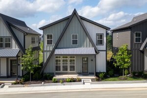 A modern two-story house with a steep A-frame roof, large front windows, and landscaped front yard sits in Nashville’s Morningside Manor neighborhood, basking in the sun on a bright day.