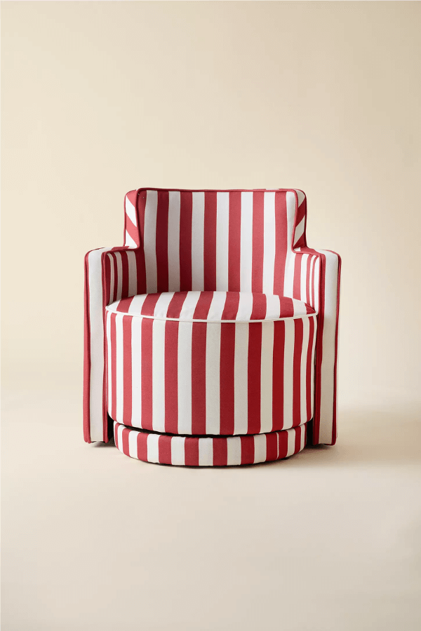 A red and white cabana stripes upholstered armchair with a circular seat and straight arms, set against a plain beige background.