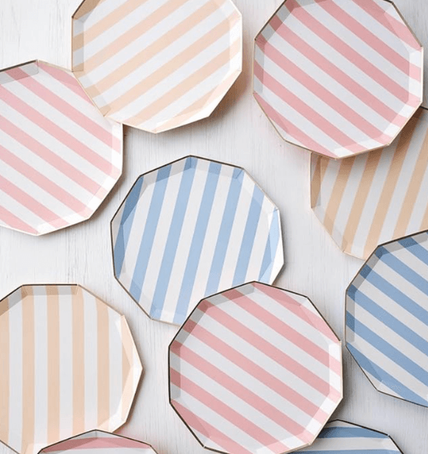 Several octagonal plates with pastel cabana-style diagonal stripes in pink, blue, and beige are arranged on a white surface.