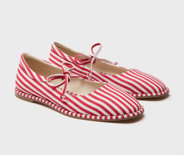A pair of red and white cabana stripes flat shoes with rounded toes, lace-up detail, and matching striped soles, displayed on a plain white background.