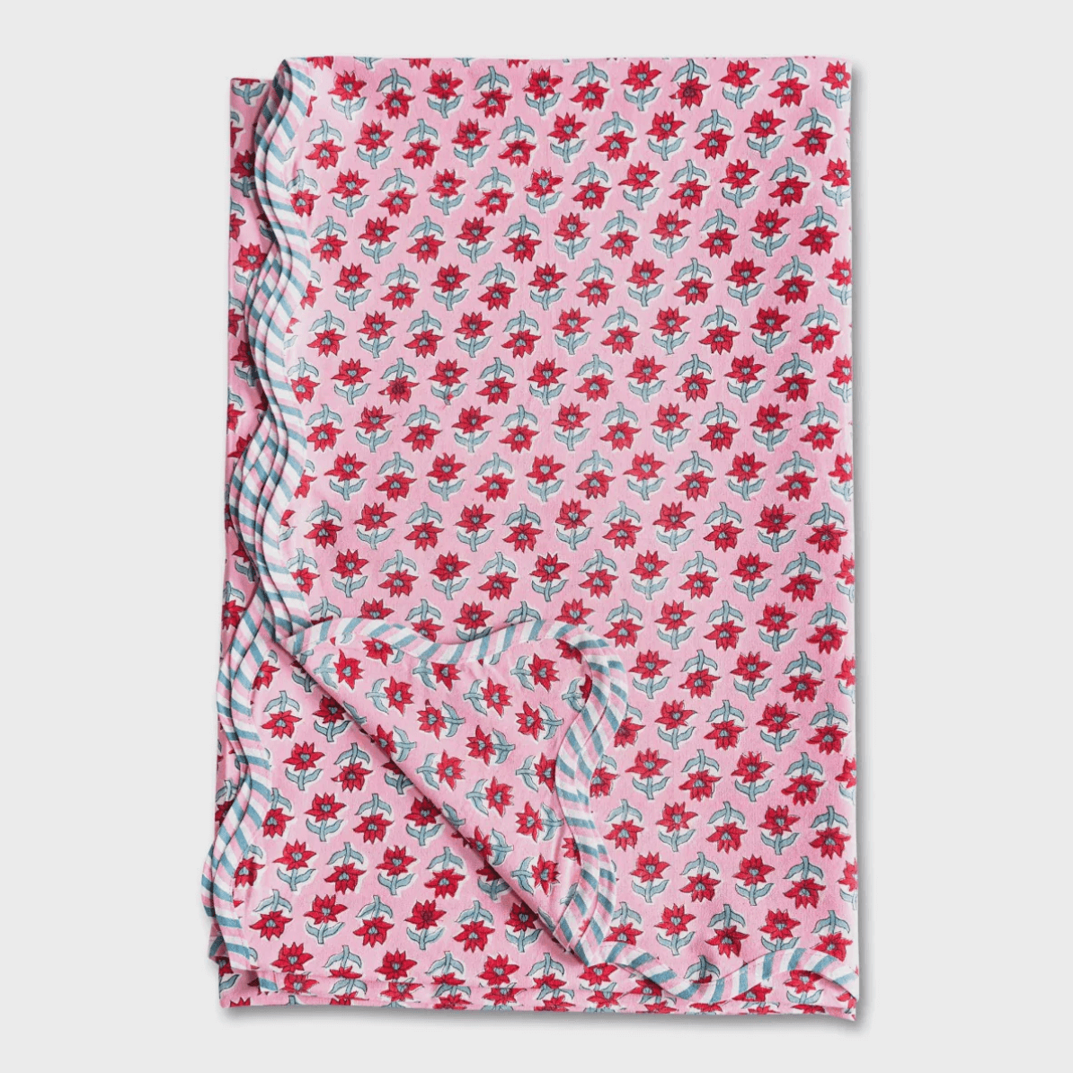 18 Nashville FINDS for Late Summer: Jewelry, Decor & More - 7 A pink floral-patterned fabric from FINDS Nashville, featuring red flowers, green leaves, and a blue-and-white striped trim—perfect for adding a touch of late summer charm, shown partially folded on a white background.