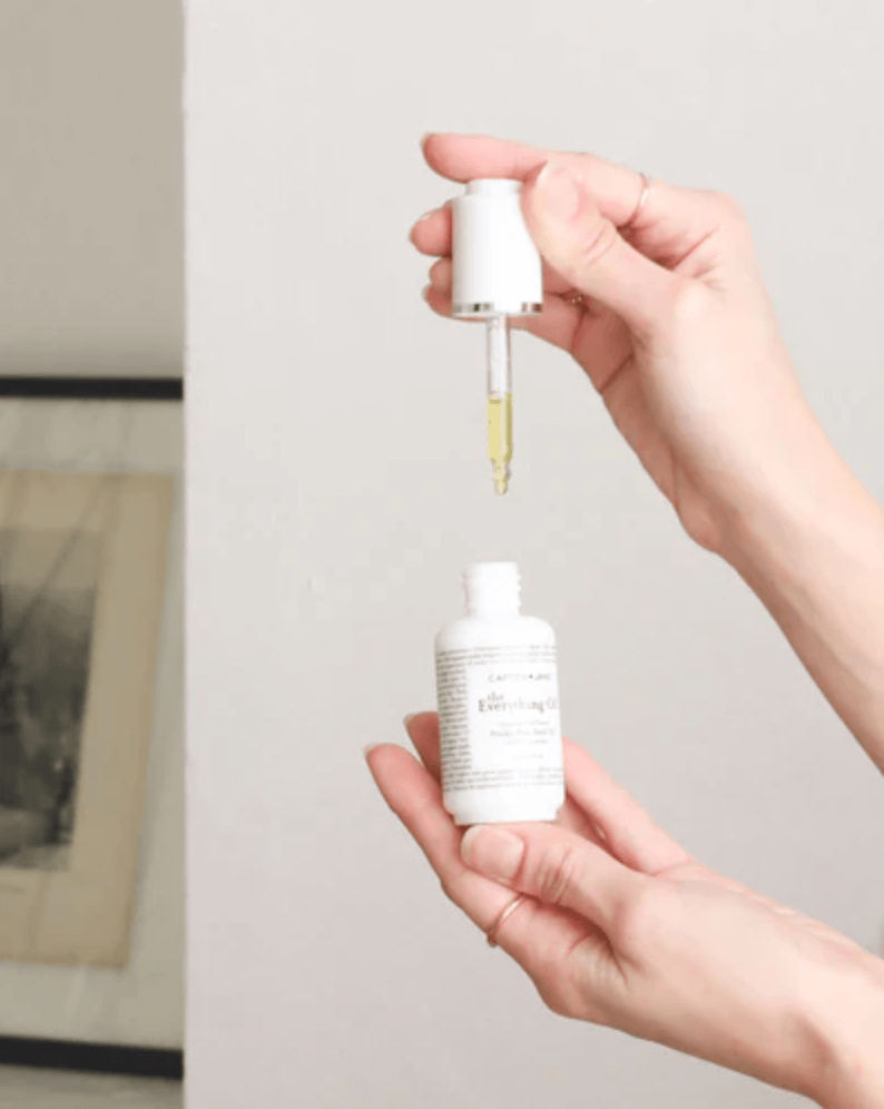 18 Nashville FINDS for Late Summer: Jewelry, Decor & More - 11 A person holds a dropper above an open skincare serum bottle, with a few drops of yellow liquid in the dropper—one of our late summer FINDS in Nashville.