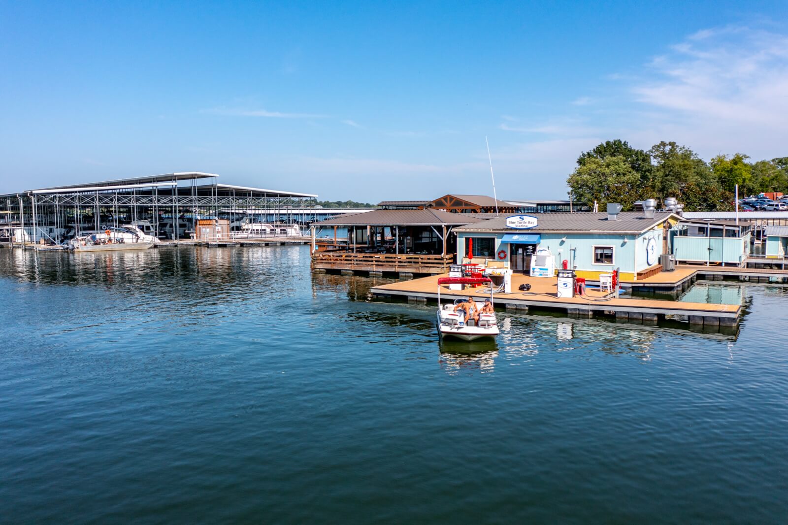 Your Guide to Old Hickory Lake - 5 A marina on Old Hickory Lake with docked boats, a floating building with a fuel station, and a large covered boat storage area—perfect for your summer guide to travel and relaxation on a sunny day.