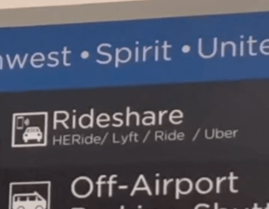 A Ride-Sharing App Driven by Women? We Love it! - 7 A directional airport sign displays rideshare options, including HERide, Lyft, Ride, and Uber, beneath airline names Southwest, Spirit, and United. HERide is clearly highlighted among the convenient transportation choices.