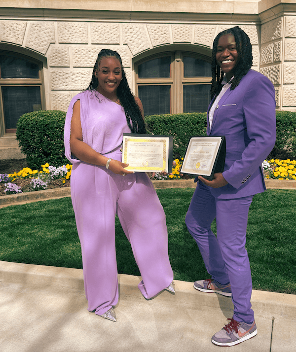 A Ride-Sharing App Driven by Women? We Love it! - 6 Two people stand outdoors in front of a building, holding certificates and smiling in matching light purple heride outfits.