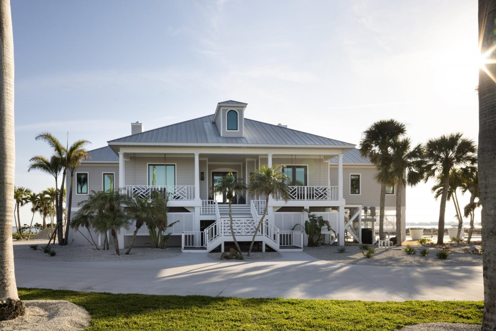 Look Inside This Effortlessly Chic Cape Haze Fishing Retreat - 1 A beach house against the ocean backdrop in Florida, surrounded by sand and palm trees.