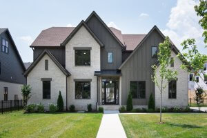 Modern two-story house at 5619 Valley View Rd, Brentwood TN, featuring light brick and dark vertical siding, large windows, a gable roof, and a landscaped front yard.