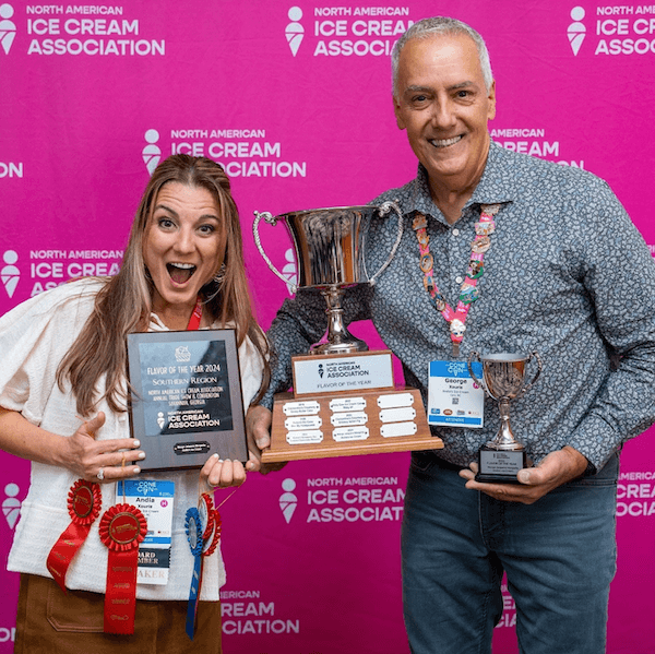 North Carolina's Hottest Ice Cream: Meet Andia's Ice Cream - 2 Two people smiling and holding trophies and ribbons in front of a North American Ice Cream Association backdrop, proudly representing Andia's Ice Cream.