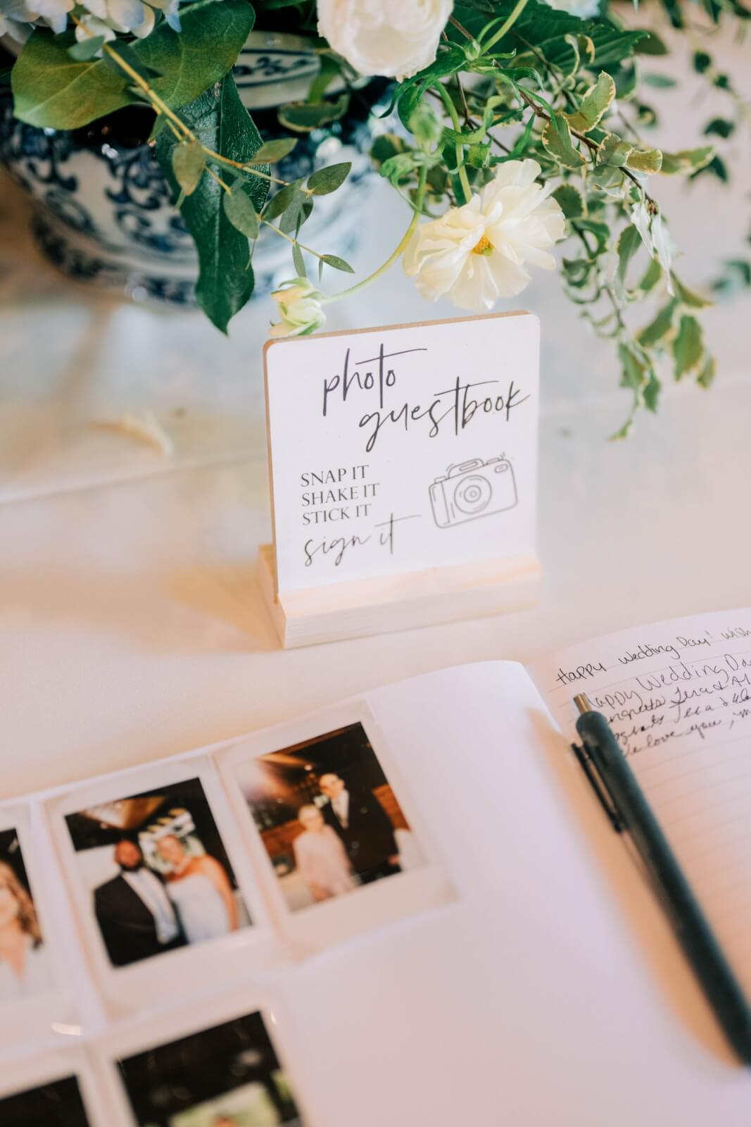 A photo guestbook display at this BHAM wedding features a sign inviting guests to snap, shake, stick, and sign beside instant photos—and even some precious pups made an appearance in the open guestbook with a pen.