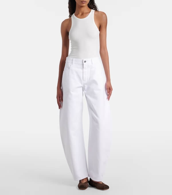 Fall 2025 Fashion: A Stylist's Lookbook of This Season's Trends - 15 A person wearing a white sleeveless top, white wide-leg pants, and brown flat shoes stands against a plain background, embodying the minimalist elegance seen in Fall 2025 fashion trends.