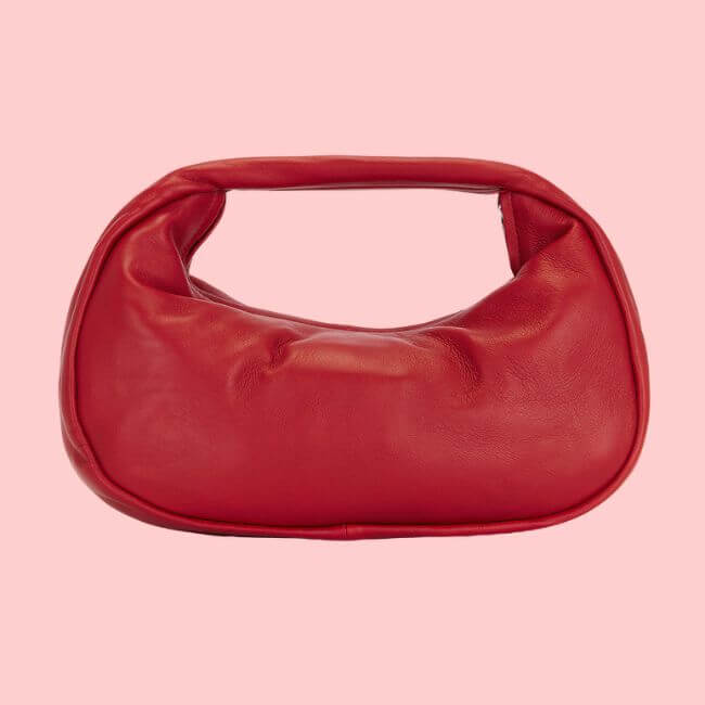 Fall 2025 Fashion: A Stylist's Lookbook of This Season's Trends - 47 A red leather handbag with a rounded shape and built-in handle, showcased against a light pink background—perfect for elevating your fall 2025 fashion.