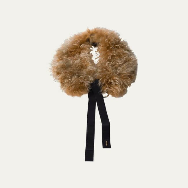 Fall 2025 Fashion: A Stylist's Lookbook of This Season's Trends - 34 A fluffy, tan faux fur collar with a black fabric tie, displayed against a plain light background—an elegant accessory inspired by Fall 2025 fashion trends.