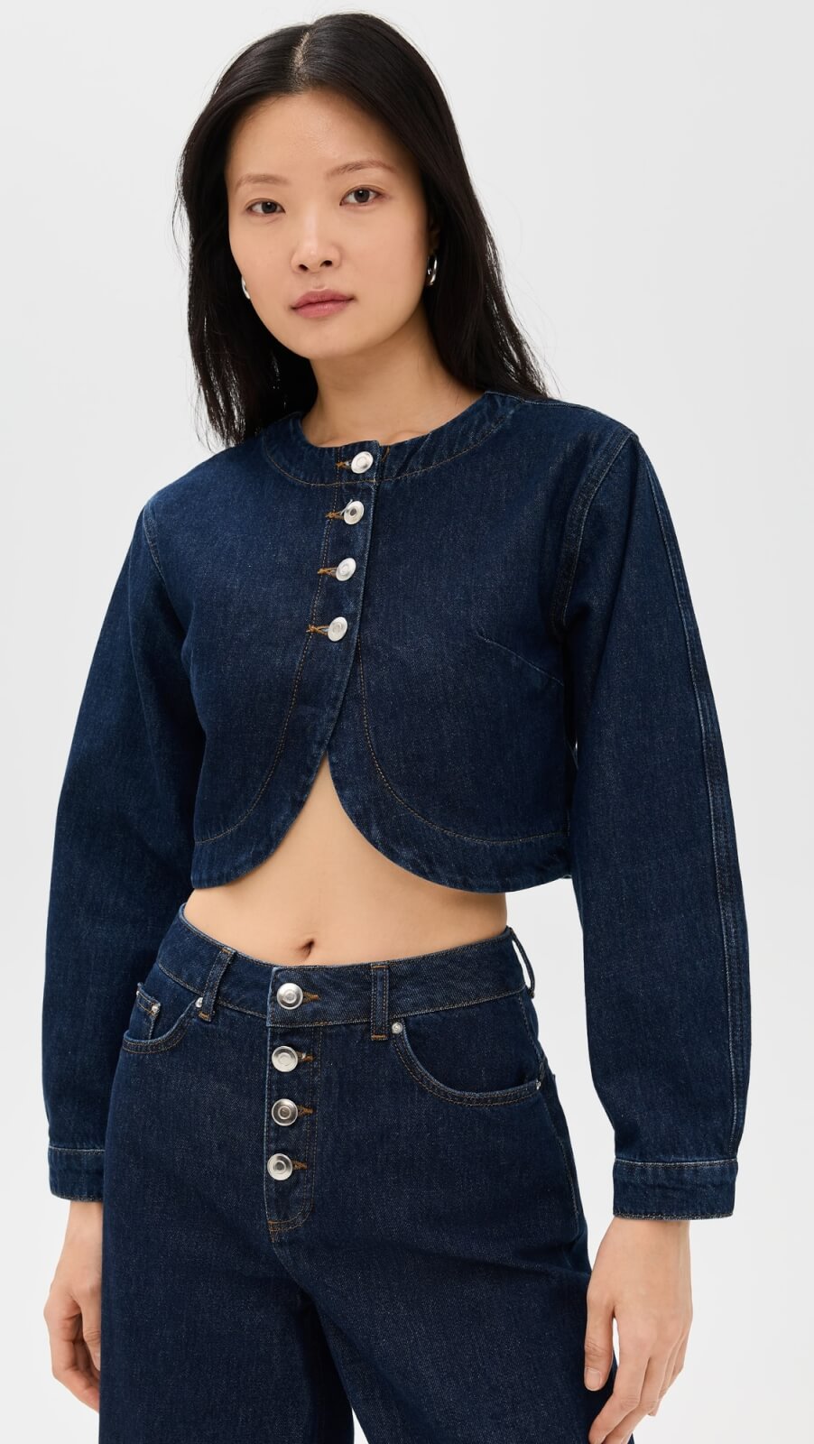 Fall 2025 Fashion: A Stylist's Lookbook of This Season's Trends - 6 Woman wearing a dark denim cropped jacket with silver buttons and matching high-waisted jeans, showcasing an effortlessly chic look perfect for fall 2025 fashion, standing against a plain light background.