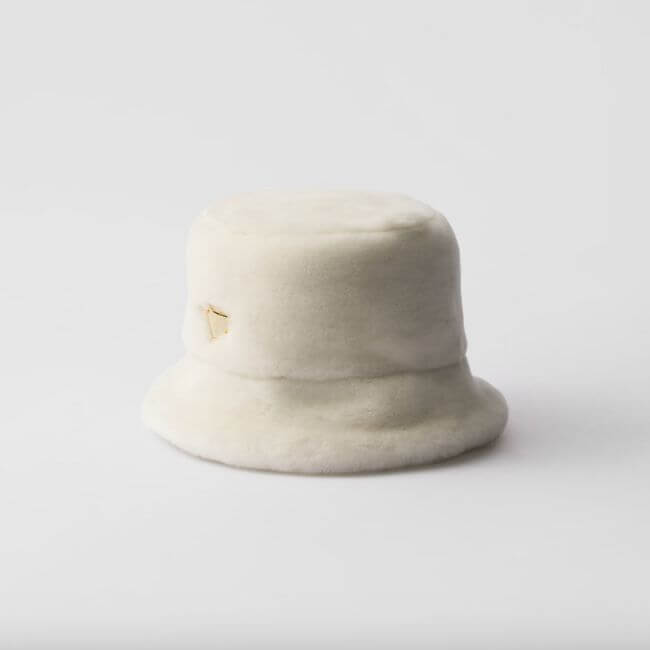 Fall 2025 Fashion: A Stylist's Lookbook of This Season's Trends - 17 A white, plush bucket hat with a small gold triangular logo on the side, displayed against a plain white background—perfect for embracing fall fashion and upcoming Fall 2025 fashion trends.