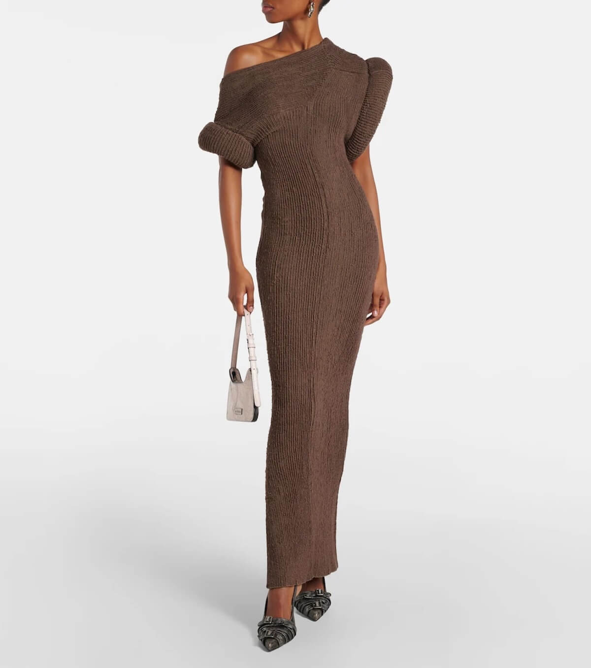 Fall 2025 Fashion: A Stylist's Lookbook of This Season's Trends - 3 A woman wearing a ribbed brown, off-the-shoulder, floor-length dress—a nod to Fall Fashion trends—carries a small handbag and wears black pointed shoes as she stands against a plain white background.
