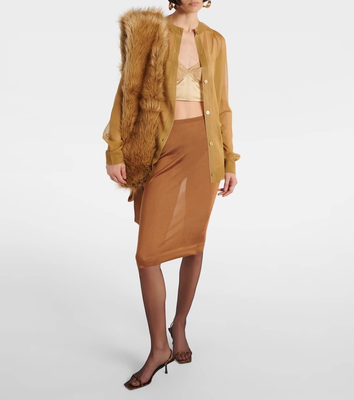 Fall 2025 Fashion: A Stylist's Lookbook of This Season's Trends - 30 A woman embraces Fall 2025 fashion in a sheer brown button-up shirt, tan crop top, brown sheer skirt, black tights, heeled sandals, and a faux fur stole draped over one shoulder—a chic nod to upcoming fashion trends.