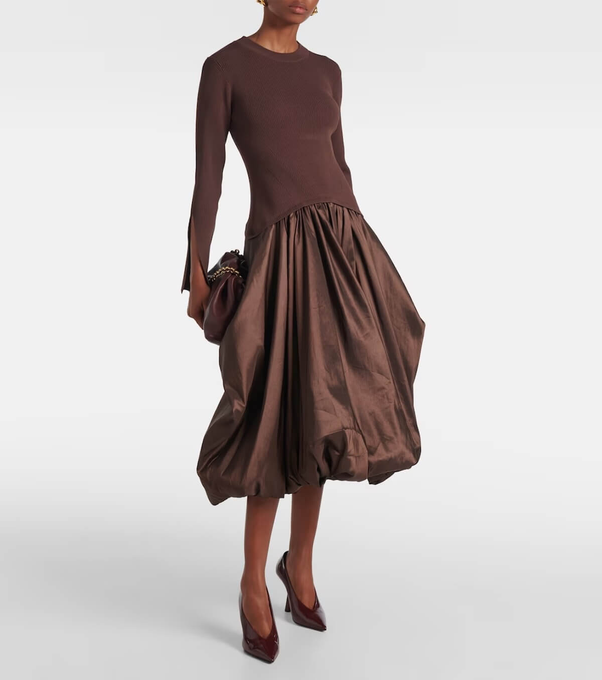 Fall 2025 Fashion: A Stylist's Lookbook of This Season's Trends - 12 A person wearing a brown long-sleeve dress with a fitted knit top and voluminous taffeta skirt, holding a brown clutch and pointed brown heels—an elegant nod to Fall 2025 fashion trends.