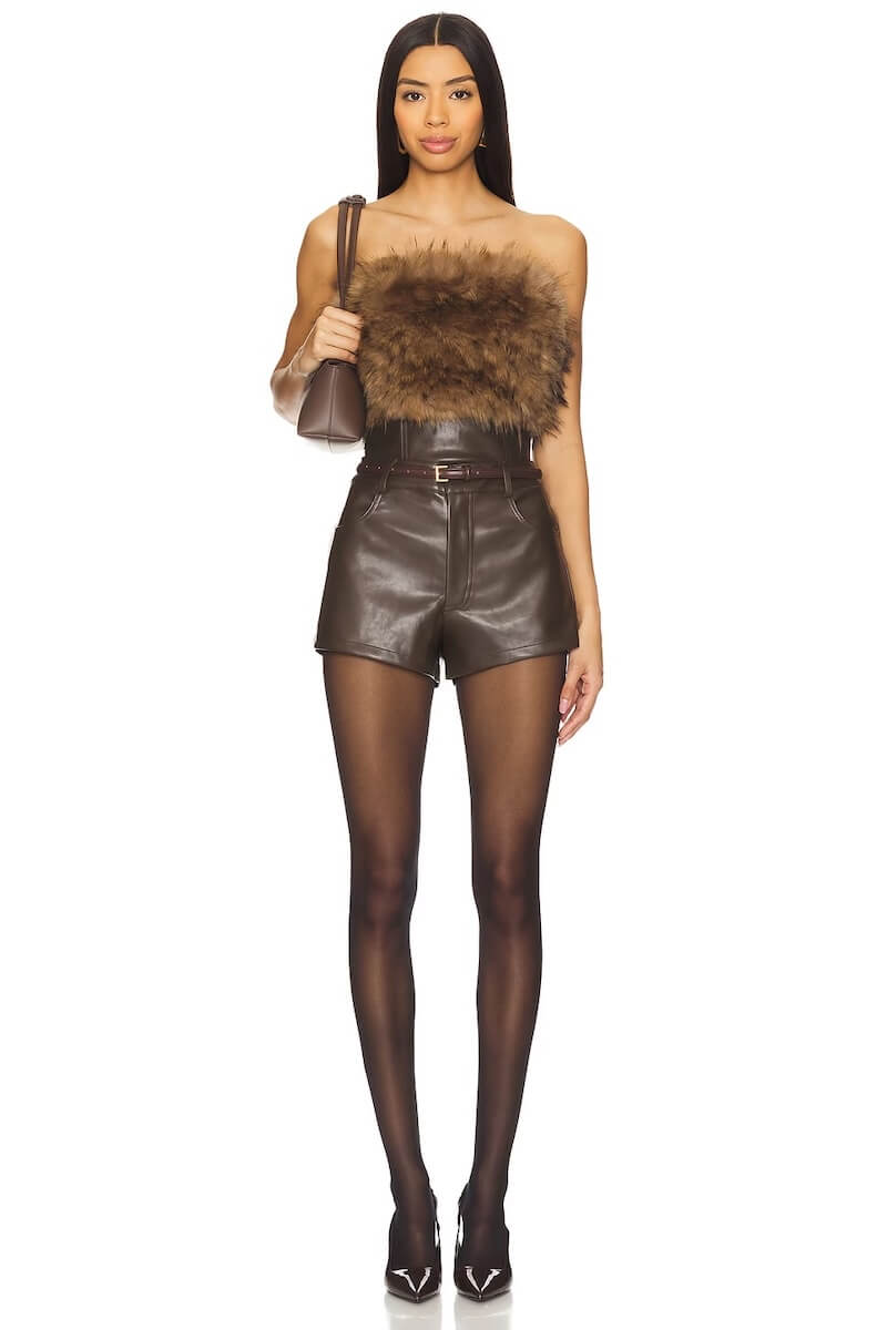 Fall 2025 Fashion: A Stylist's Lookbook of This Season's Trends - 31 A woman wearing a brown fur strapless top, high-waisted brown leather shorts, sheer black tights, pointed heels, and carrying a small brown bag—a chic look inspired by fall 2025 fashion.