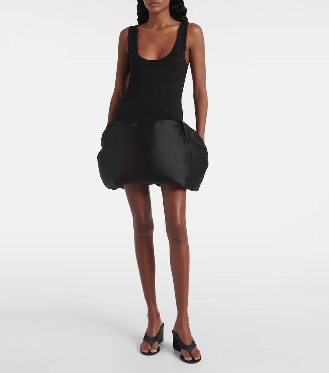 Fall 2025 Fashion: A Stylist's Lookbook of This Season's Trends - 9 A woman wearing a sleeveless black bodysuit with a voluminous bubble skirt and black heeled mules stands against a plain white background, showcasing one of the bold fashion trends for Fall 2025.