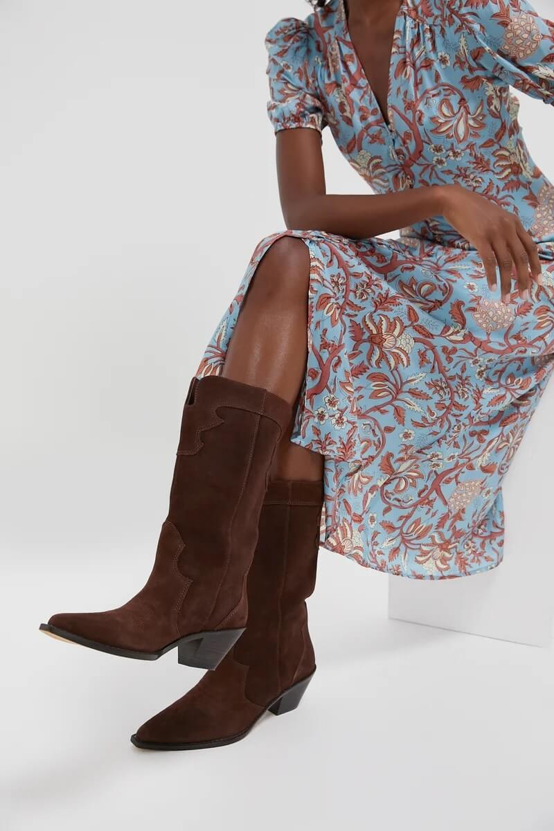 Fall 2025 Fashion: A Stylist's Lookbook of This Season's Trends - 60 A person wearing a blue floral dress and dark brown suede knee-high boots, embodying Fall 2025 fashion trends, sits on a white surface.