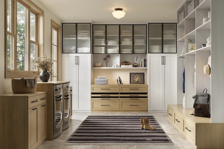 Modern laundry room with wood cabinetry, front-load washer and dryer, built-in shelves by California Closets, storage cabinets, and a striped rug. A single boot and a basket rest on the floor, adding charm to this Memphis space.