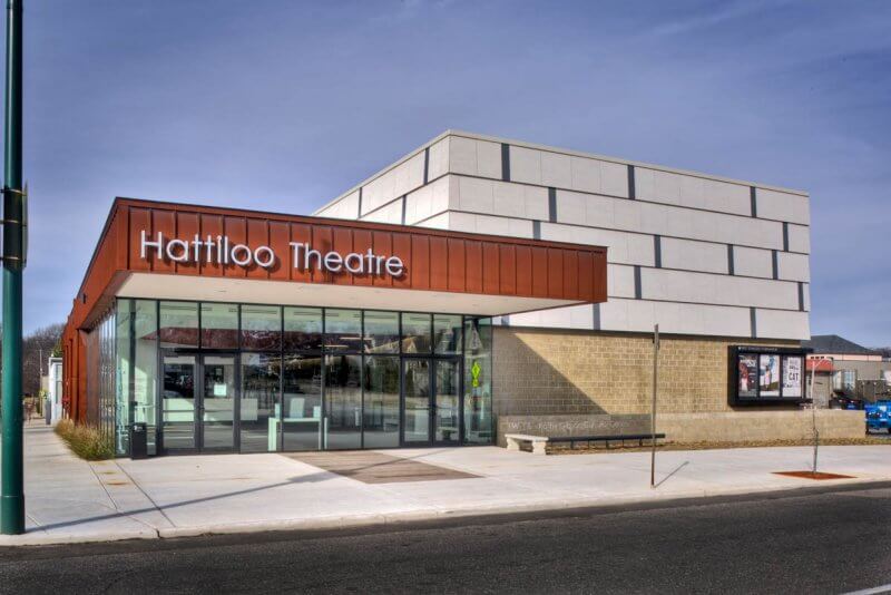 Modern exterior of Hattiloo Theatre with a red-brown facade, large glass windows, and bold signage—an iconic spot for live theater in Memphis, showcasing outstanding plays and musicals under the clear city sky.