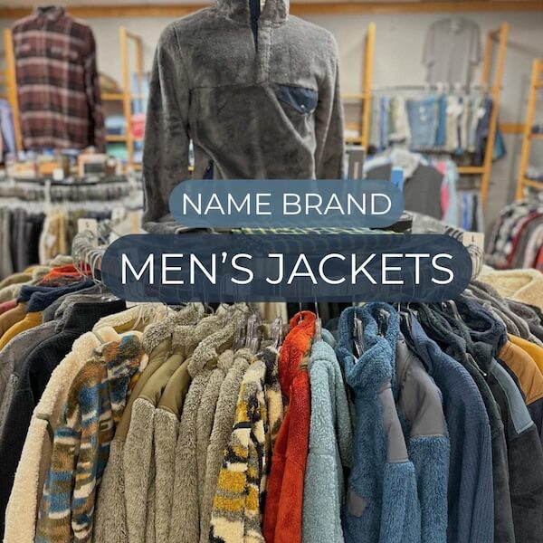 A rack of assorted men's jackets in various colors and textures, displayed beneath a sign reading "Name Brand Men's Jackets"—a stylish find often spotted in discount stores.
