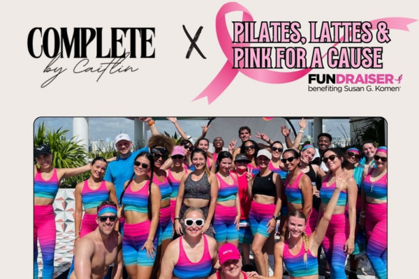 A group of people in matching rainbow workout outfits pose together at an outdoor Pilates, Lattes & Pink For A Cause charity fundraiser benefiting Susan G. Komen.