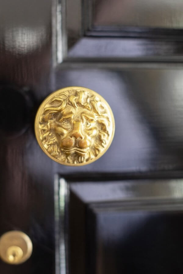 Close-up of a shiny gold lion's head door knob on a glossy black door, adding a touch of Buckhead elegance to your Atlanta home.