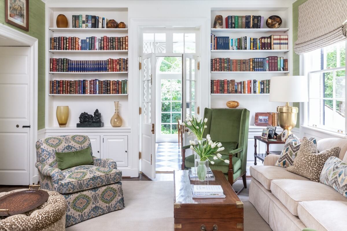 A bright Buckhead living room with built-in bookshelves, an armchair, a sofa, a wooden coffee table, and large windows filling the home with natural light.