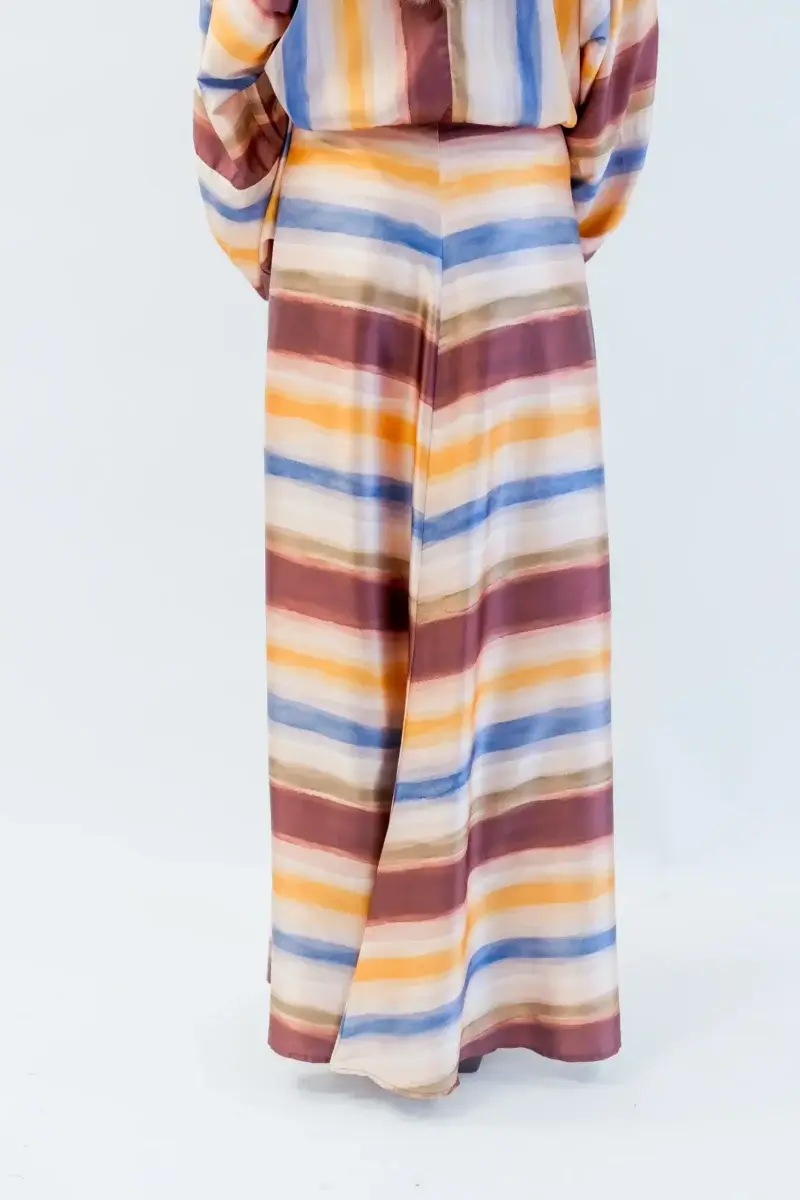 Person wearing a long skirt with horizontal stripes in earthy tones—one of the standout Birmingham finds this October—standing against a plain background.