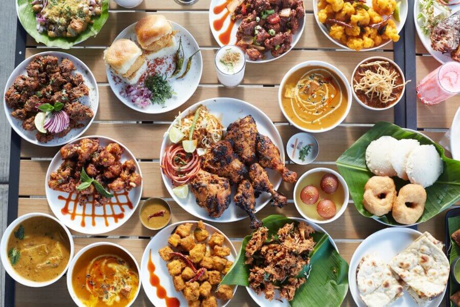Memphis’s 10 Most Popular Articles of 2025 - 2 An overhead view of a table filled with various Indian dishes, including grilled meats, curries, rice, breads, fried snacks, and desserts on white plates at one of the top new Memphis restaurants.